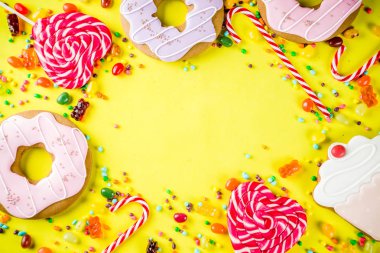 Tatlılar yaratıcı paralamak, lolipop, reçel, şeker, çerezleri çörek ve cupcakes, parlak sarı arka plana üstten görünüm kopya alanı ile tatlı kavramı
