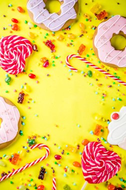 Tatlılar yaratıcı paralamak, lolipop, reçel, şeker, çerezleri çörek ve cupcakes, parlak sarı arka plana üstten görünüm kopya alanı ile tatlı kavramı