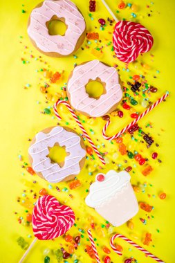 Tatlılar yaratıcı paralamak, lolipop, reçel, şeker, çerezleri çörek ve cupcakes, parlak sarı arka plana üstten görünüm kopya alanı ile tatlı kavramı