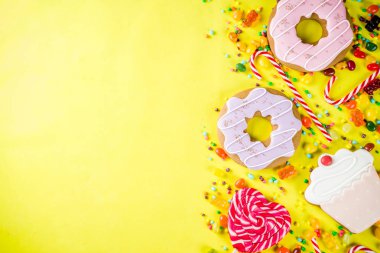 Tatlılar yaratıcı paralamak, lolipop, reçel, şeker, çerezleri çörek ve cupcakes, parlak sarı arka plana üstten görünüm kopya alanı ile tatlı kavramı