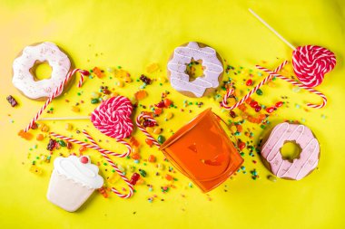 Cadılar Bayramı tatlılar kavramı, şenlikli bir kabak, şekerleme ve şeker, tanımlama bilgileri, reçel, tatlılar, parlak sarı arka plana üstten görünüm kopya alanı tam formunda kova