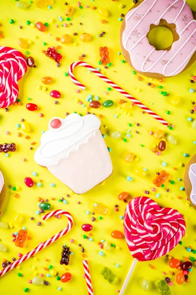 Tatlılar yaratıcı paralamak, lolipop, reçel, şeker, çerezleri çörek ve cupcakes, parlak sarı arka plana üstten görünüm kopya alanı ile tatlı kavramı