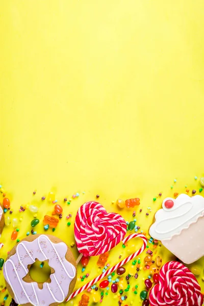 Tatlılar yaratıcı paralamak, lolipop, reçel, şeker, çerezleri çörek ve cupcakes, parlak sarı arka plana üstten görünüm kopya alanı ile tatlı kavramı