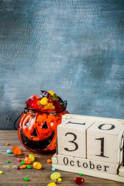 Cadılar Bayramı kutlama konseptiyle kabak dekorasyon, şeker, jack o fener Kupası ve eski tarz ahşap takvim, mavi ve ahşap arka plan, kopya alanı
