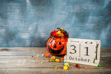 Cadılar Bayramı kutlama konseptiyle kabak dekorasyon, şeker, jack o fener Kupası ve eski tarz ahşap takvim, mavi ve ahşap arka plan, kopya alanı