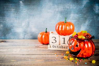 Cadılar Bayramı kutlama konseptiyle kabak dekorasyon, şeker, jack o fener Kupası ve eski tarz ahşap takvim, mavi ve ahşap arka plan, kopya alanı