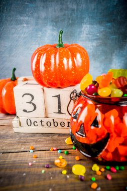 Cadılar Bayramı kutlama konseptiyle kabak dekorasyon, şeker, jack o fener Kupası ve eski tarz ahşap takvim, mavi ve ahşap arka plan, kopya alanı