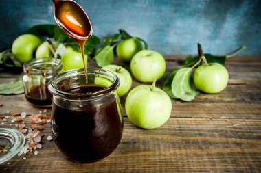 Ev yeşil elma, ahşap ve koyu mavi arka plan ile karanlık tuzlu klasik karamel sos pişmiş,