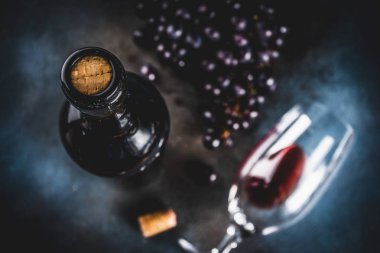 Cam ve üzüm ile kırmızı şarap şişesi, koyu arka plan kopya alanı üstten görünüm seçici odak