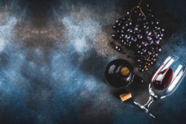 Cam ve üzüm ile kırmızı şarap şişesi, koyu arka plan kopya alanı üstten görünüm seçici odak