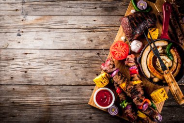 Çeşitler çeşitli barbekü yemek ızgara et, Barbekü partisi fest - şiş kebap, sosis, ızgara et fileto, taze sebze, soslar, baharatlar, kopya alanı yukarıda eski ahşap rustik masa üzerinde