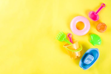 Yaz tatil kavramı ile plastik beach çocuklar oyuncak - kepçe, kepçe, Komisyon, kalıpları tekne, lifebuoy oyuncaklar alan sarı arka plan kopyalayın.