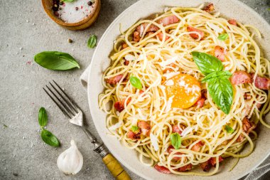 Geleneksel İtalyan Makarna, spagetti carbonara pastırma, krem sos, parmesan peyniri, yumurta sarısı ve taze fesleğen yaprakları gri taş arka plan kopya alanı