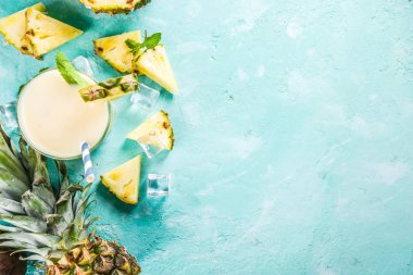 Serinletici yaz içki, kokteyl, üzerinde adet ananas, Hindistan cevizi, buz ve nane yaprakları ile bir açık mavi renkli ev yapımı pina colada alanı üst görünüm Kopyala