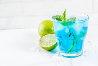 Renkli yaz yiyecek, içecek, buzlu mavi lagün alkol kokteyl içki limon ve nane, beyaz mermer zemin kopya alanı ile