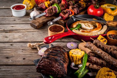 Çeşitler çeşitli barbekü yemek ızgara et, Barbekü partisi fest - şiş kebap, sosis, ızgara et fileto, taze sebze, soslar, baharatlar, kopya alanı yukarıda eski ahşap rustik masa üzerinde