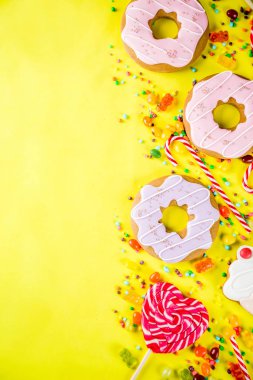 Tatlılar yaratıcı paralamak, lolipop, reçel, şeker, çerezleri çörek ve cupcakes, parlak sarı arka plana üstten görünüm kopya alanı ile tatlı kavramı