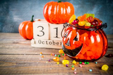 Cadılar Bayramı kutlama konseptiyle kabak dekorasyon, şeker, jack o fener Kupası ve eski tarz ahşap takvim, mavi ve ahşap arka plan, kopya alanı