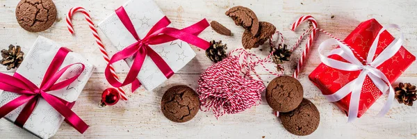 Christmas background with decorations, chocolate cookies and gift boxes on wooden background top view copy space banner