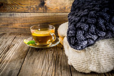 Sonbahar konfor ve sıcak kavramı. Çay cam bardağı limon, nane ve baharatlar, sıcak battaniye ile eski rustik ahşap arka plan üzerinde. Metin için yer kopyalayın