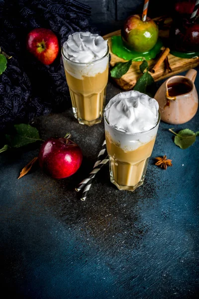 Spiced Caramel Apple or apple pie smoothie, organic autumn fruit cocktail with whipped cream, On a dark background, with apples, leaves, caramel sauce and a warm blanket. Copy space for text