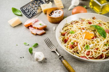 Geleneksel İtalyan Makarna, spagetti carbonara pastırma, krem sos, parmesan peyniri, yumurta sarısı ve taze fesleğen yaprakları gri taş arka plan kopya alanı