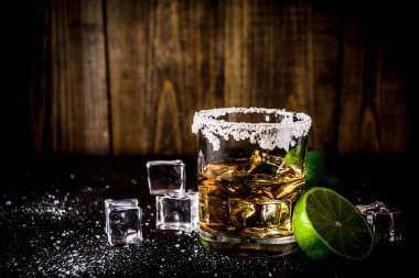 İki tekila shot bardağı buz küpleriyle koyu arka plan üzerine tuz ve limes alanı Kopyala