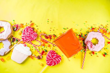 Cadılar Bayramı tatlılar kavramı, şenlikli bir kabak, şekerleme ve şeker, tanımlama bilgileri, reçel, tatlılar, parlak sarı arka plana üstten görünüm kopya alanı tam formunda kova