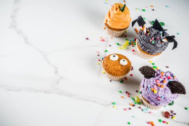 Cadılar Bayramı için komik çocuk davranır: varyasyonları cupcakes, farklı canavarlar, Cadılar, pumpkins, hayaletler şeklinde dekore edilmiştir. Beyaz mermer zemin kopya alanı metin için,