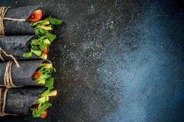 Trendy sağlıklı vegan gıda. Siyah kömür kaydırılan sandviçle, taze sebze, peynir, üzerinde koyu mavi arka plan, metin için yer