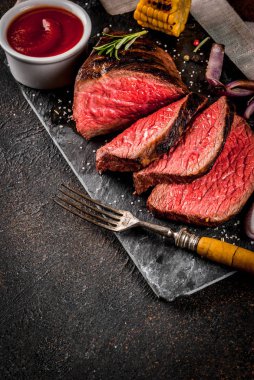 Taze ızgara sığır eti, ev yapımı barbekü et orta pişmiş, baharatlar, koyu arka plan, kopya alanı ile siyah taş kesme tahtası üzerinde