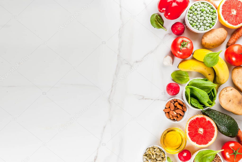 Healthy food background, trendy Alkaline diet products - fruits, vegetables, cereals, nuts. oils, white marble background above copy space