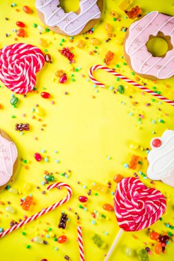 Tatlılar yaratıcı paralamak, lolipop, reçel, şeker, çerezleri çörek ve cupcakes, parlak sarı arka plana üstten görünüm kopya alanı ile tatlı kavramı