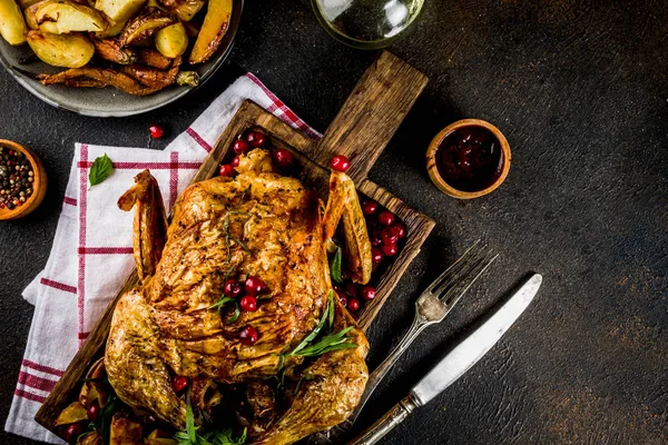 Christmas, thanksgiving food, baked roasted chicken with cranberry and herbs, served with fried vegetables and sauces on dark rusty table, copy space above