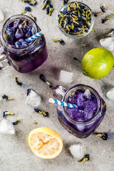 健康的な夏冷たい飲み物 アイス ライムとレモン 灰色のコンクリート背景コピー スペース平面図有機青と紫の蝶エンドウ豆の花茶 — ストック写真