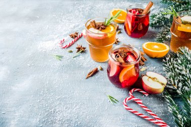 Geleneksel kış içecekler, beyaz ve kırmızı mulled şarap kokteyl ile beyaz ve kırmızı şarap, baharat, elma, portakal. Üzerinde mavi masa lambası,