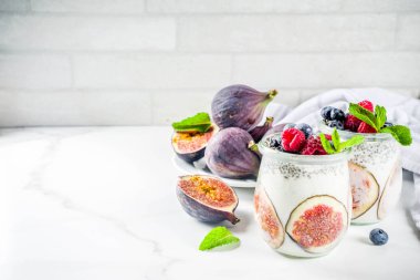 Sağlıklı detoks kahvaltı meze - yoğurt güler yüzlü veya milkshake incir, yaban mersini, ahududu chia tohumu, beyaz mermer zemin, kopya alanı ile