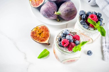 Sağlıklı detoks kahvaltı meze - yoğurt güler yüzlü veya milkshake incir, yaban mersini, ahududu chia tohumu, beyaz mermer zemin, kopya alanı ile