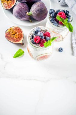 Sağlıklı detoks kahvaltı meze - yoğurt güler yüzlü veya milkshake incir, yaban mersini, ahududu chia tohumu, beyaz mermer zemin, kopya alanı ile