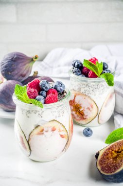 Sağlıklı detoks kahvaltı meze - yoğurt güler yüzlü veya milkshake incir, yaban mersini, ahududu chia tohumu, beyaz mermer zemin, kopya alanı ile