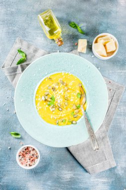 Balkabağı parmesan çorbası kabak çekirdeği, fesleğen yaprakları ve parmesan peyniri wit, mavi arka plan kopya alanı yukarıdan ışık