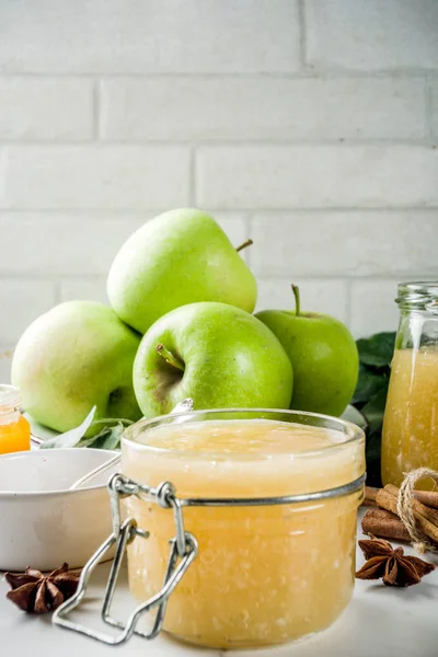 Homemade apple jam or sauce, with green apples and spices, white marble background copy space