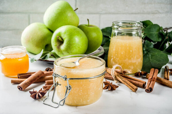 Homemade apple jam or sauce, with green apples and spices, white marble background copy space