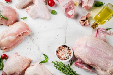 Çiğ tavuk, tavuk eti - bacaklar, kanatlar, fileto meme, bütün, ham - baharat ve otlar pişirme için farklı türde dilimlenmiş. Bir beyaz mermer masa, üstten görünüm kopya alanı