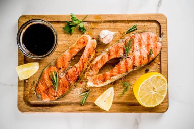 Izgara Somon Balık biftek malzemeler limon, otlar, zeytin yağı, kayrak kesme tahtası, karanlık paslı arka plan kopya alanı ile