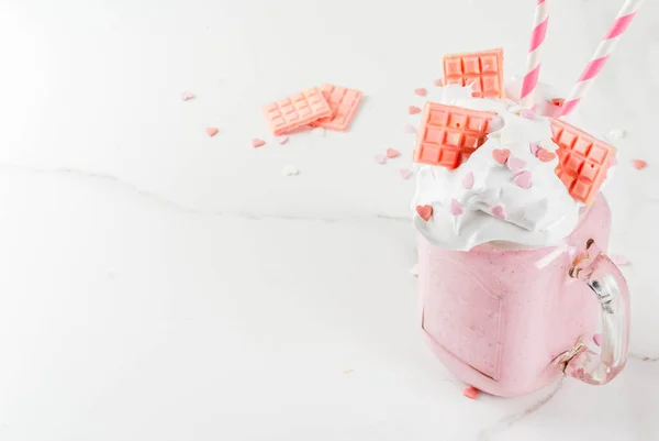 Crazy shake, romantic milkshake for Valentine's day with strawberry, white chocolate and sugar candy hearts, on white background, copy space