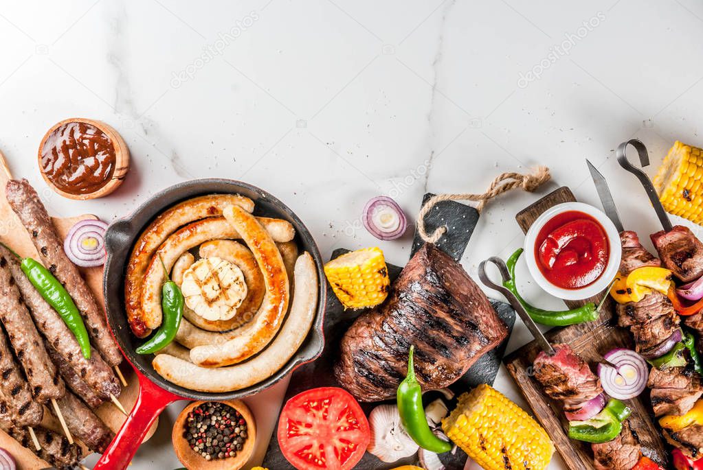 Assortment various barbecue food grill meat, bbq party fest - shish kebab, sausages, grilled meat fillet, fresh vegetables, sauces, spices, white marble background, above copy space