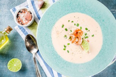 Akdeniz İtalyan geleneksel yemekleri, ev yapımı sebze deniz ürünleri krem çorbası karides karides, kireç ve otlar, açık mavi beton renkli kopya alanı yukarıdaki