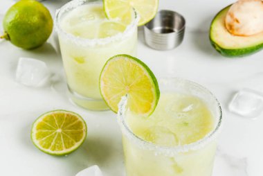 Alkollü kokteyl tarifleri ve fikirler. Beyaz mermer mutfak masası üzerinde tuz ile avokado ve kireç margarita. Kopya alanı