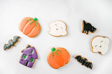 Geleneksel Cadılar Bayramı pastası, çocuklar için komik kurabiyeler hayalet, balkabağı, kara kedi, yarasalar, cadı evi. Eski ahşap masa üzerinde, üst görünüm kopyalama alanı, tarifler için not defteri ile